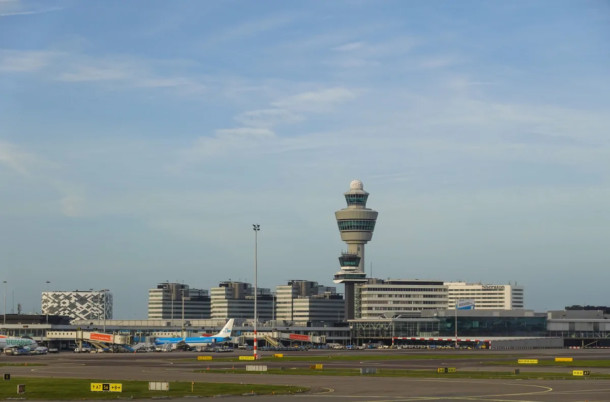 Amsterdam Schiphol Airport with the control tower, terminal, and aircraft on the apron