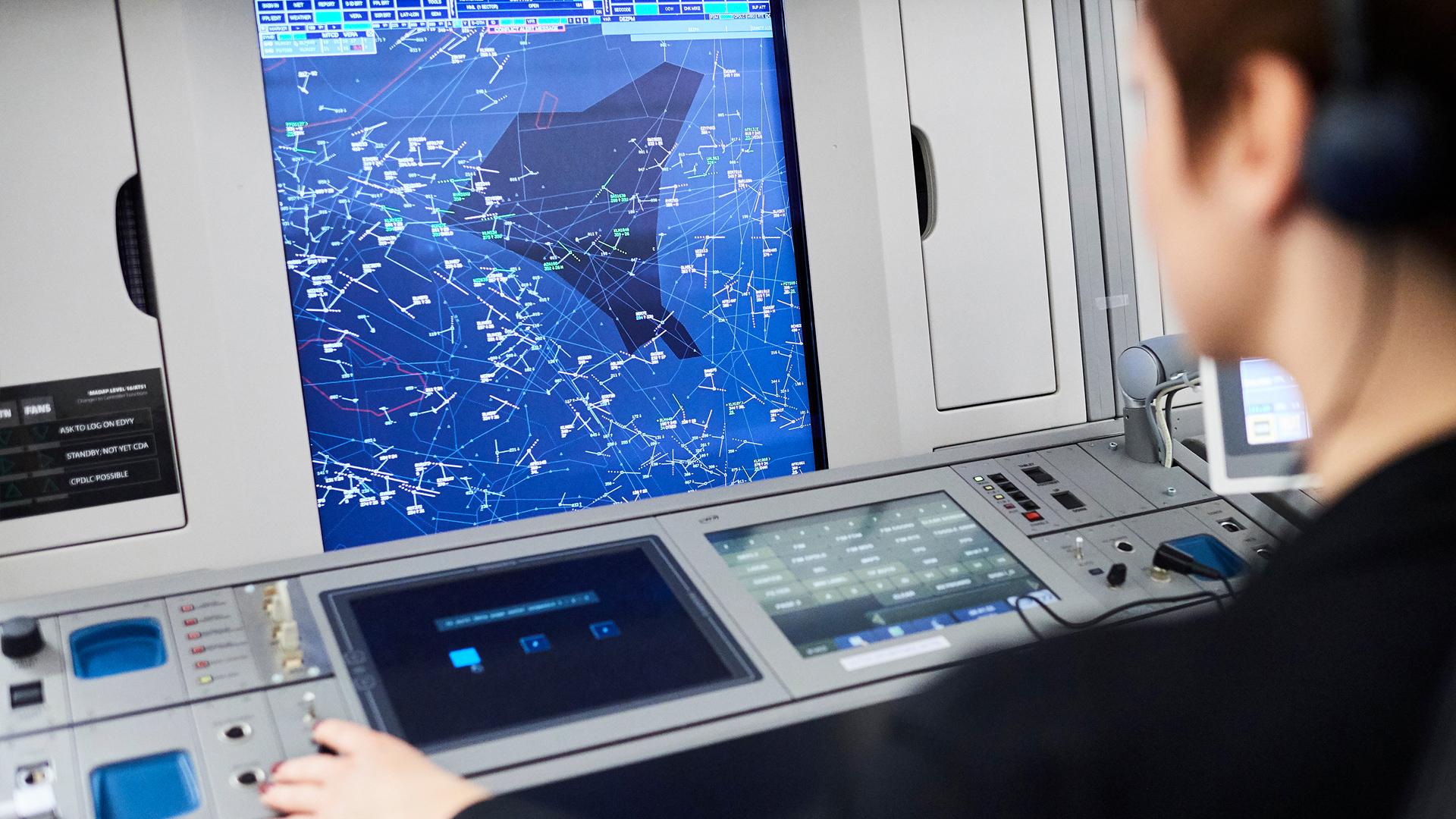 Air traffic controller monitoring radar display with flight paths and aircraft data